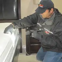 Bed bug inspection technician checking a mattress and bed frame for signs of infestation in Marietta, GA