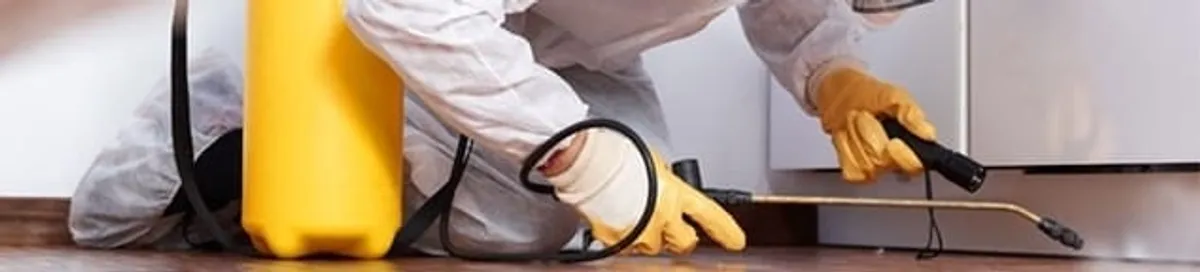 Roach exterminator treating cracks and crevices along kitchen baseboards in Marietta, GA
