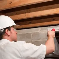 Termite inspection technician checking a basement wall and framing for termite activity in Marietta, GA