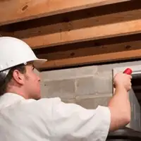 Termite inspection technician checking a basement wall and framing for termite activity in Marietta, GA